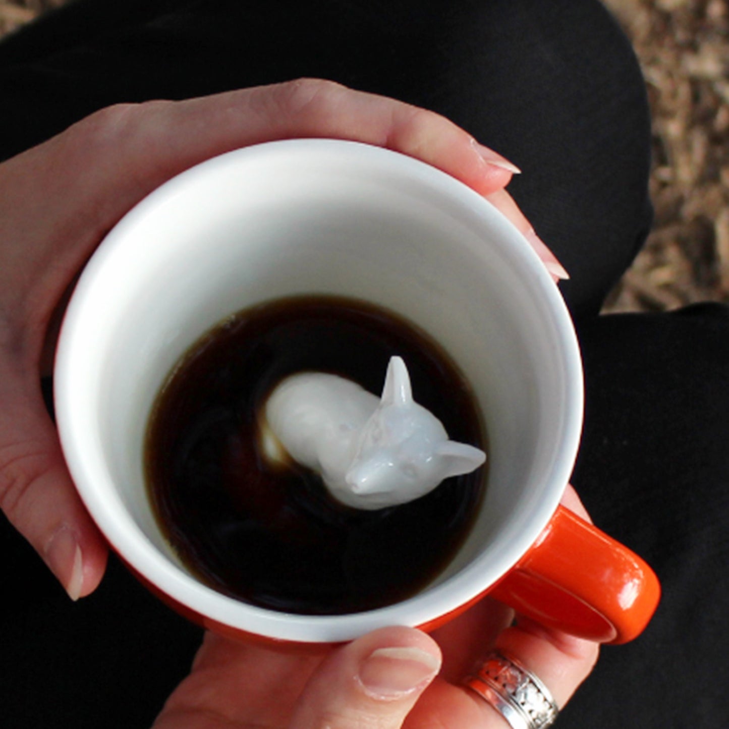 Red orange Fox Creature Cup interior partially submerged being held in a lap with both hands