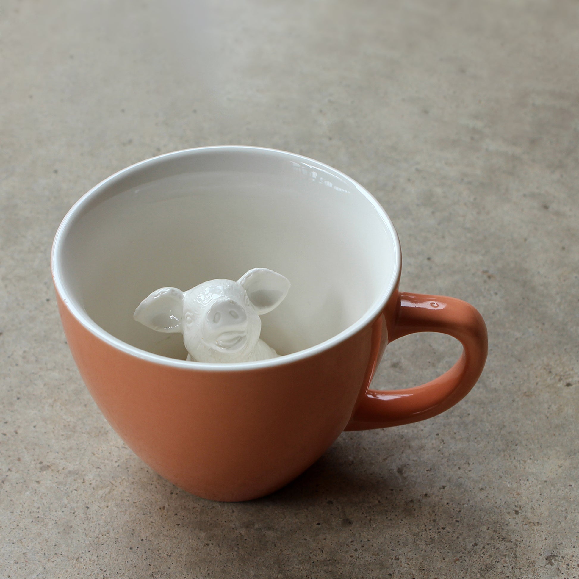 Peach Pig Creature Cup exterior partially submerged on concrete