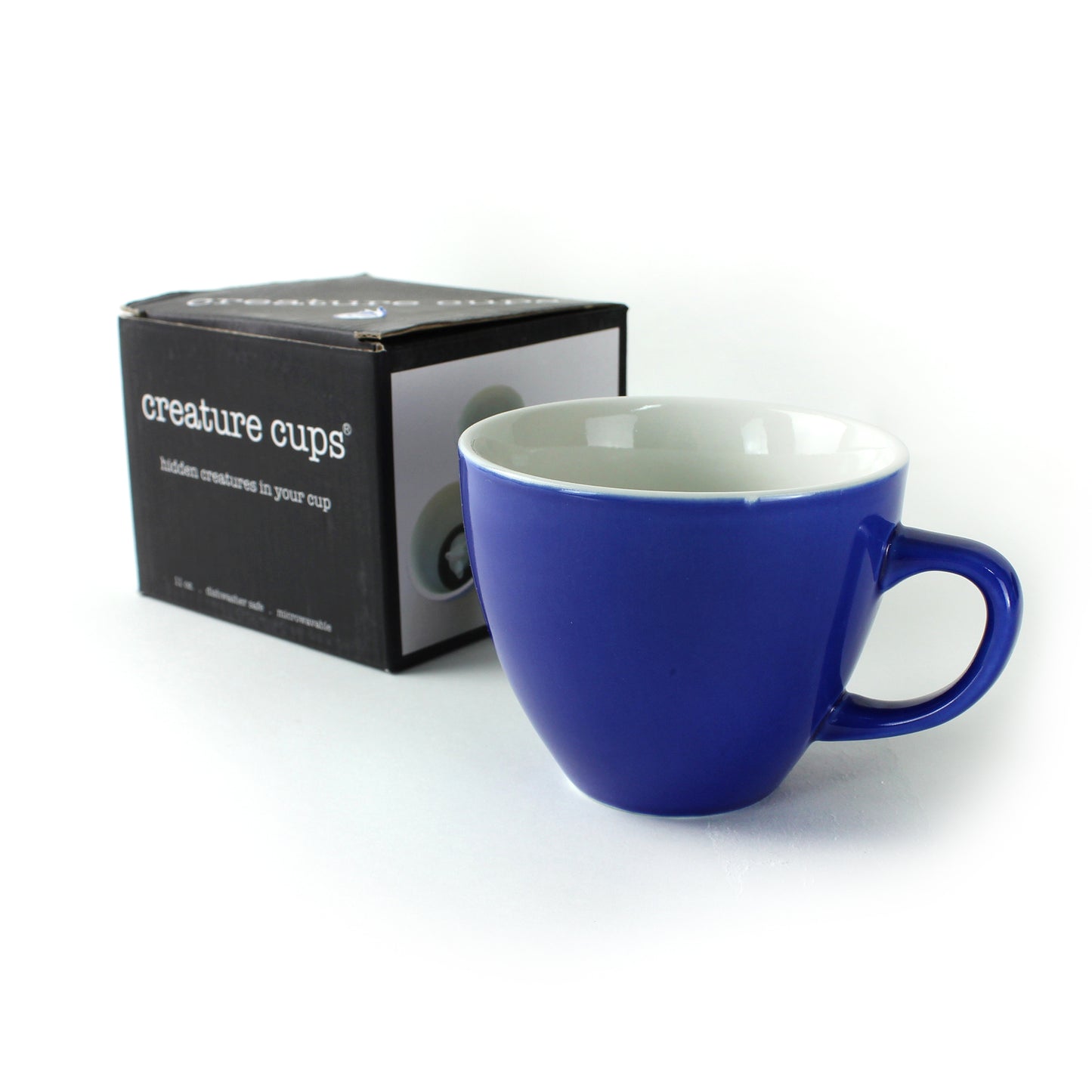 Cobalt Blue colored Creature Cup sitting in front of packaging