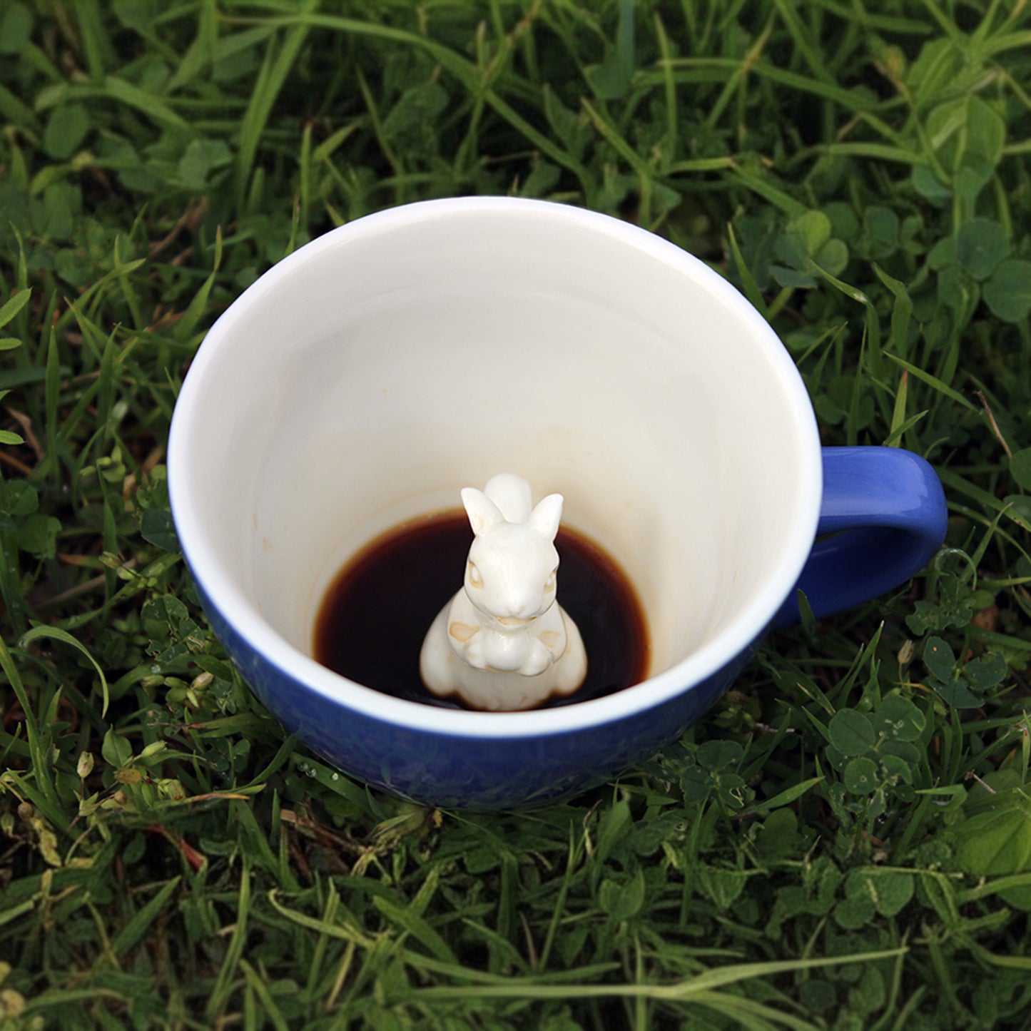 Cobalt Blue colored Squirrel Creature cup partially submerged sitting on top of grass