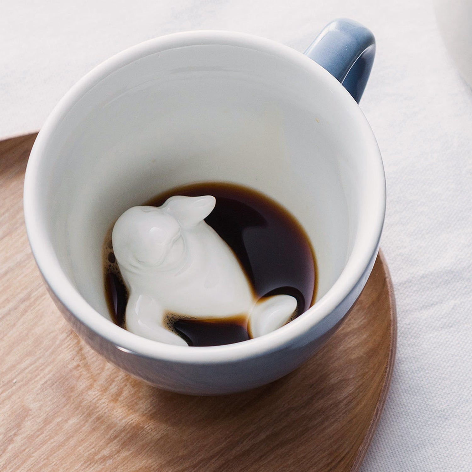 Pale Blue Manatee Creature Cup sitting on a wooden tray