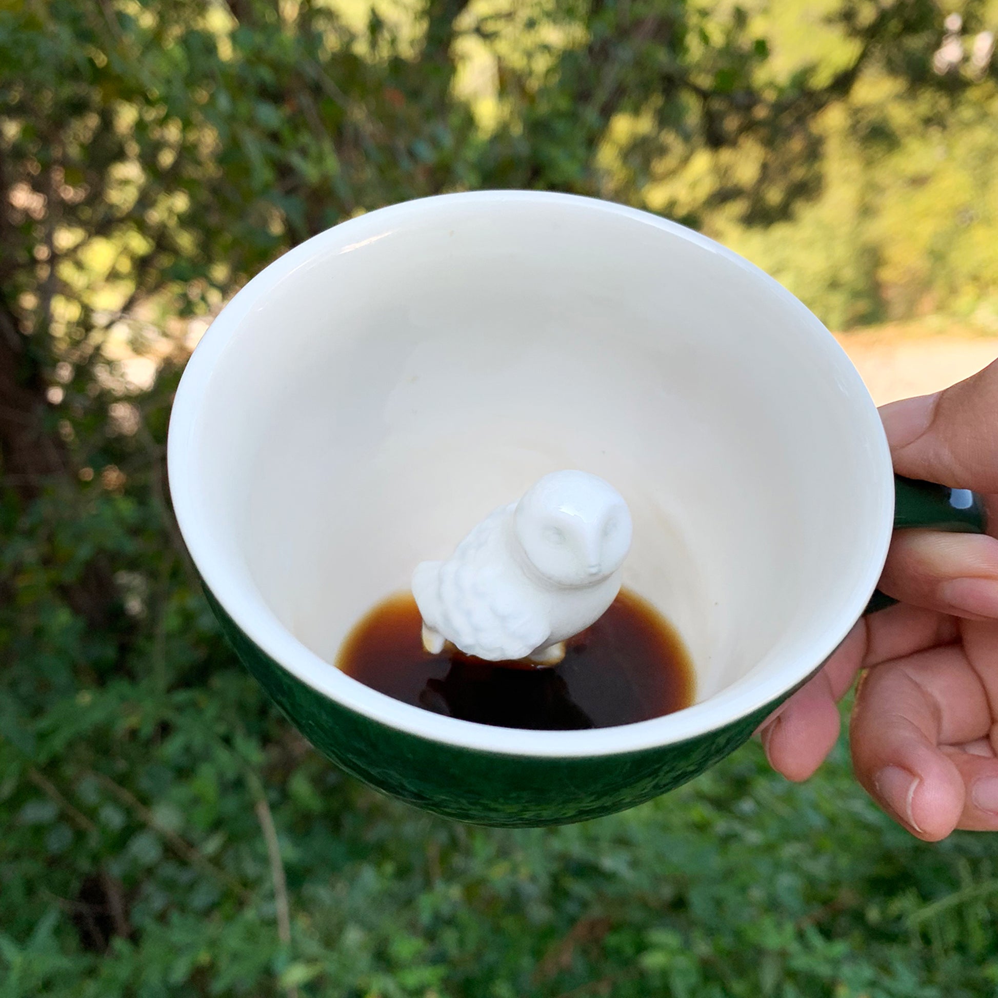 Emerald green Owl Creature Cup interior being held in front of bushes