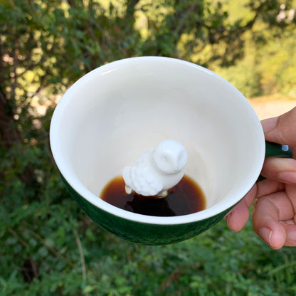 Emerald green Owl Creature Cup interior being held in front of bushes