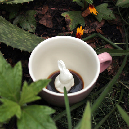 Blush pink rabbit Creature Cup sitting in a patch of brush