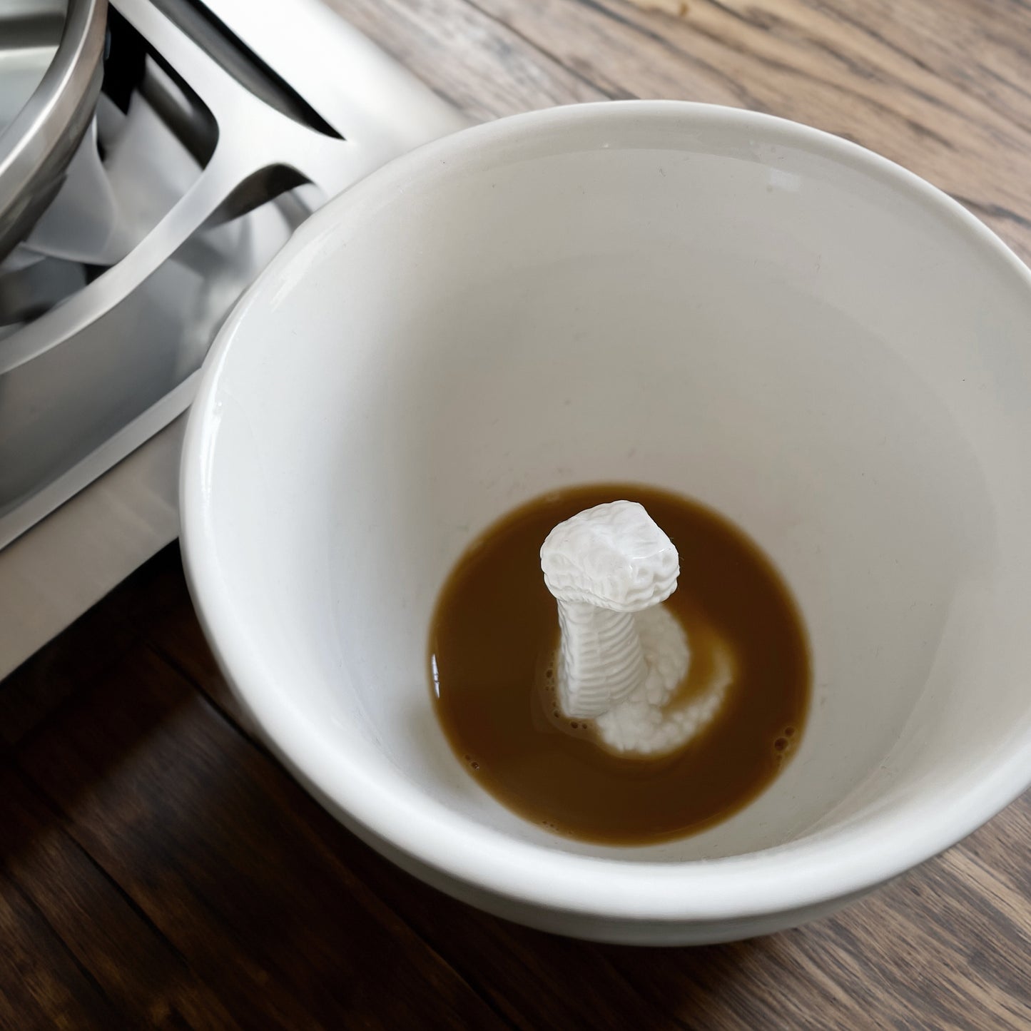 Matte olive brown snake Creature Cup interior on a wooden countertop next to a stove